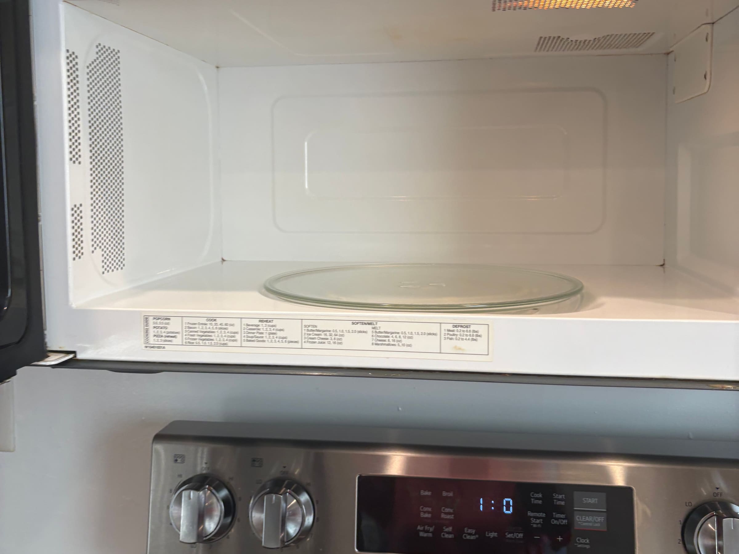 The inside of a microwave after a move-out clean, cavity and glass turntable clear.