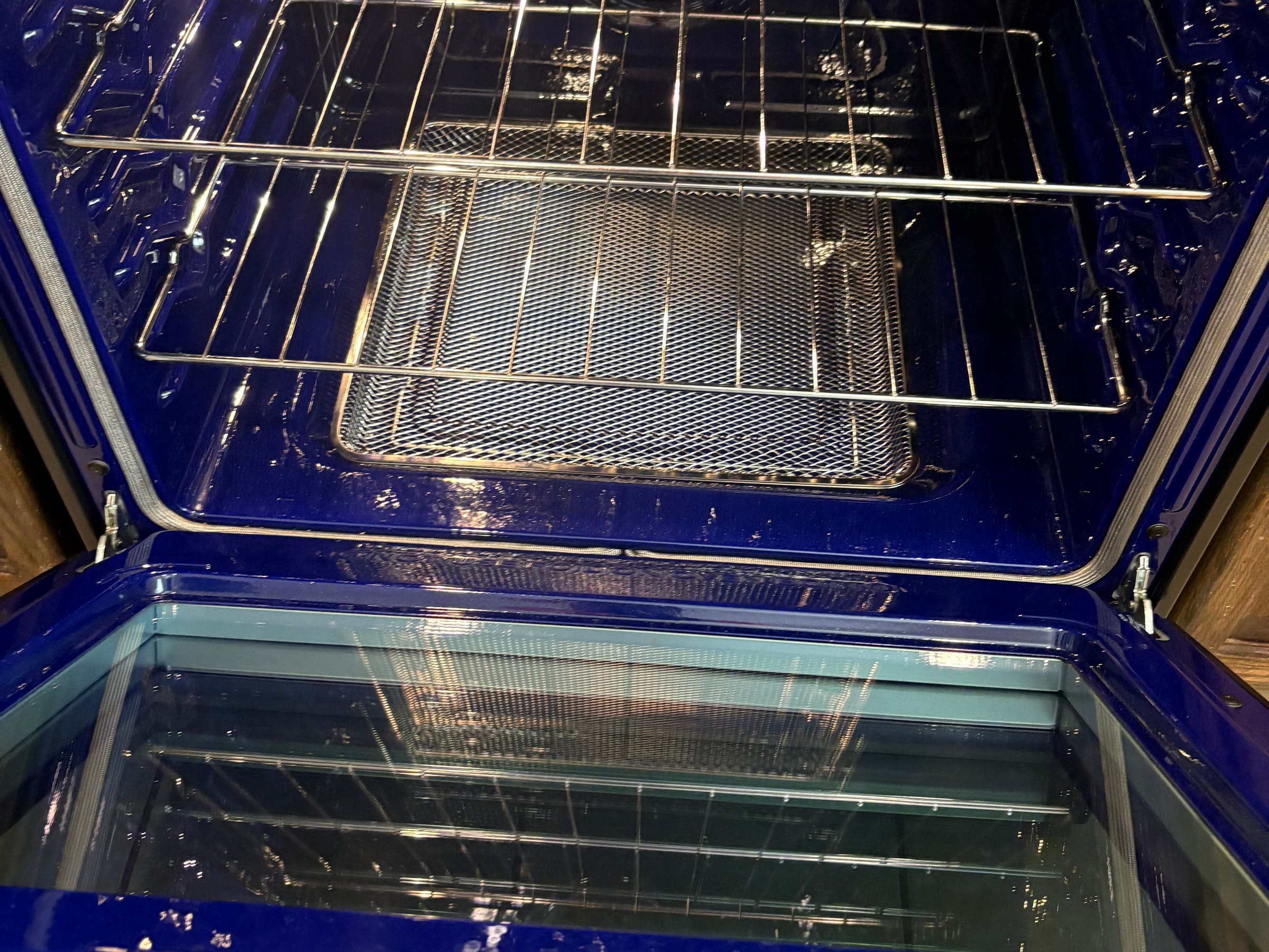 The inside of an oven after a move-out clean, blue enamel and wire racks clear of grease.